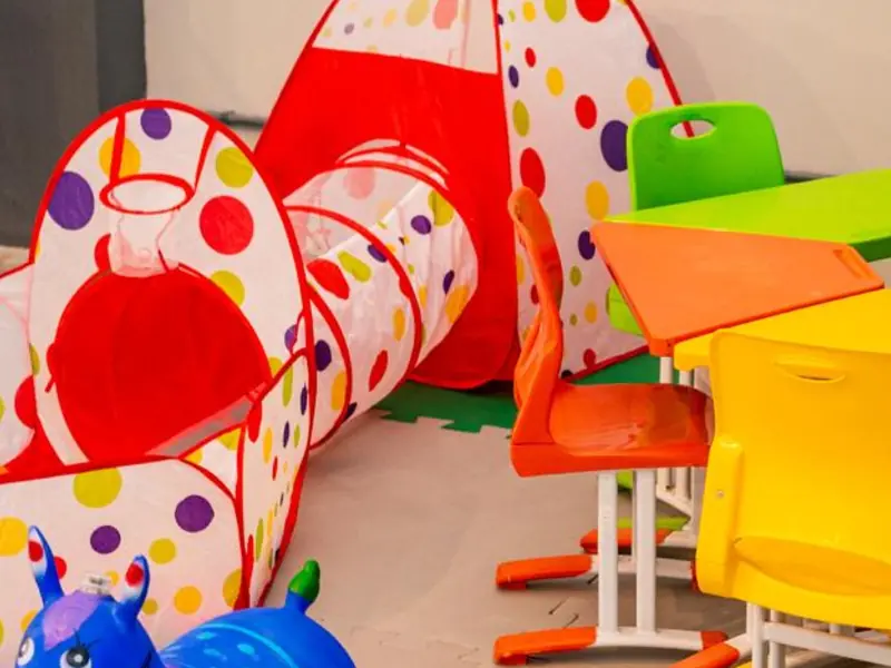Espaço Kids com tenda, túnel de brincar e mesinhas coloridas