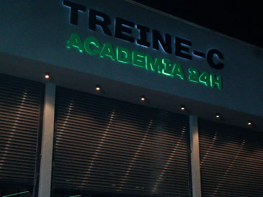 Fachada da unidade 24 Horas à noite, com letreiro Treine-C iluminado em verde